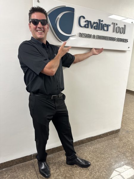 Cavalier Tool President, Brian Bendig posing with the Cavalier Tool India Sign. He is smiling and pretending to hold up the sign.