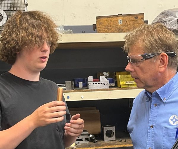 Logan showing Career Ready Monitor Richard Janik a component he works with in the detail room at Cavalier Tool.